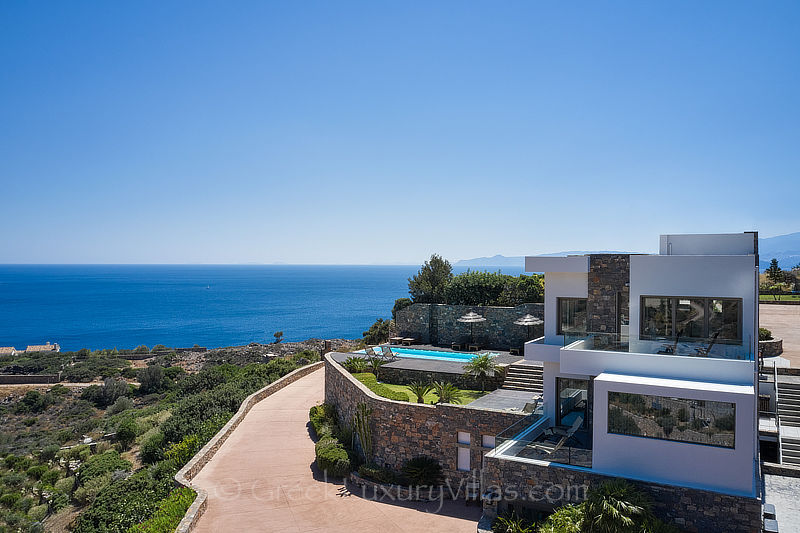 aerial view of modern luxury villa with heated pool overlooking elounda bay Crete