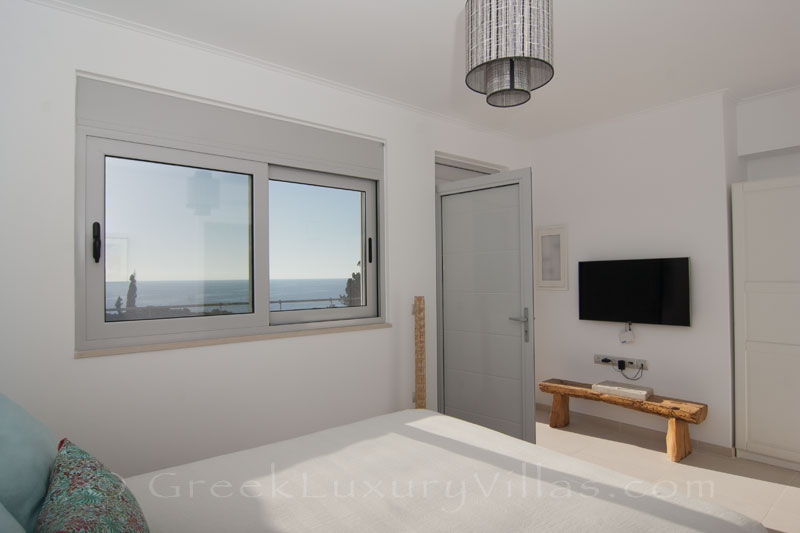 A bedroom with seaview in the guest house of a modern luxury villa with a pool in Paxos